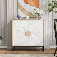 a white and gold cabinet with an abstract painting on the wall in front of it