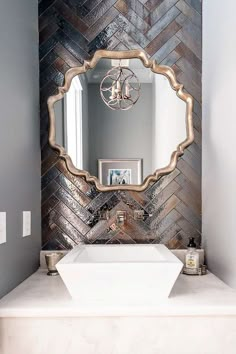 a white sink sitting under a mirror next to a wall mounted faucet in a bathroom