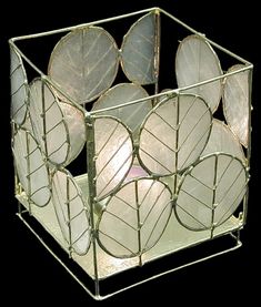 a decorative glass box with leaves on the inside and sides, holding several lit candles