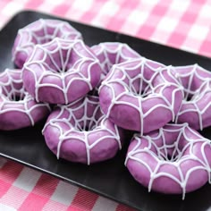 purple sprinkled donuts on a black plate with pink and white checkered tablecloth