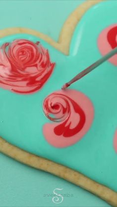 a heart shaped cookie being decorated with icing