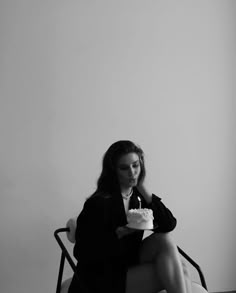 a woman sitting in a chair holding a cake