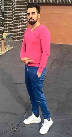 a man in pink shirt and blue pants posing for the camera with his hand on his hip