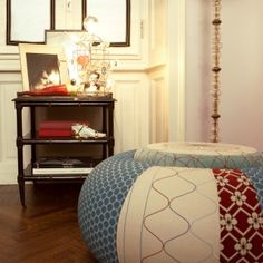 a large round ottoman sitting on top of a hard wood floor next to a white wall