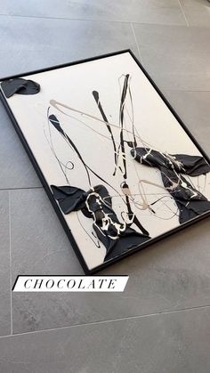 a black and white painting sitting on top of a floor next to a sign that says chocolate