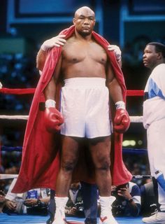 two men standing next to each other wearing boxing gloves and red capes on their shoulders