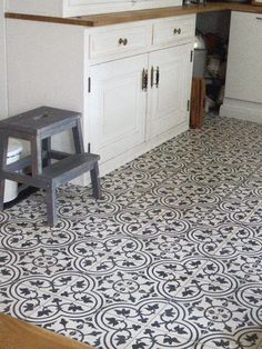 a kitchen with white cabinets and black and white floor tiles on the floor, along with a step stool