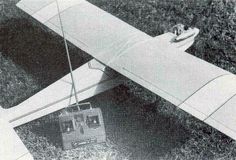 an airplane with a radio attached to it sitting in the grass next to a suitcase