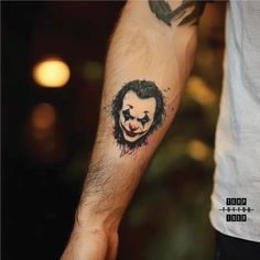 a man with a tattoo on his arm that has a clown's face painted on it