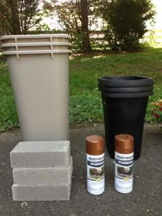 three cans and two trash cans sitting next to each other on the ground in front of a garbage can