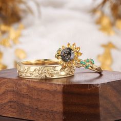 two gold wedding rings sitting on top of a wooden table next to other jewelry items