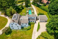 an aerial view of a large house with a pool in the center and lots of trees surrounding it