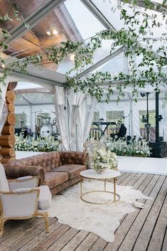 a living room filled with furniture and flowers on top of a wooden floor covered in greenery