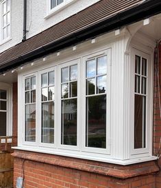 a brick house with white windows and red bricks on the outside wall, along with an awning