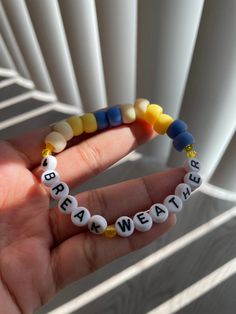 a hand holding a beaded bracelet with words written on it that spell out break weather