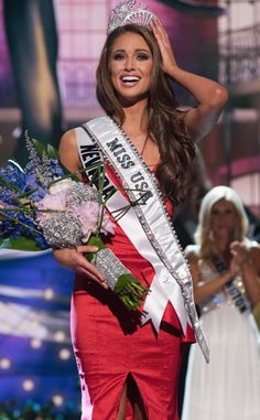 a woman in a red dress holding flowers and a tiara with the word miss usa on it