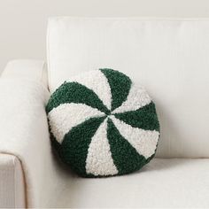 a green and white striped pillow sitting on top of a couch next to a white chair