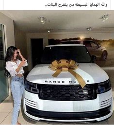 a woman standing next to a range rover with a bow on it