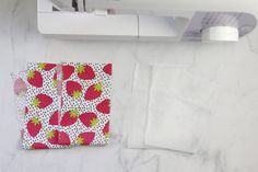 a piece of paper with strawberries on it next to a sewing machine