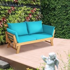 a blue couch sitting on top of a wooden floor next to a green plant wall