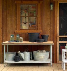 pots and pans are sitting on an old table in front of a wooden house