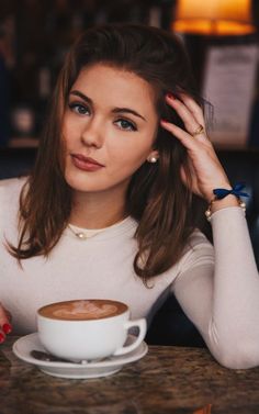 a woman sitting at a table with a cup of coffee