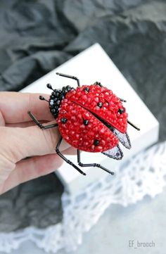 a lady bug brooch sitting on top of a white box with black beads around it