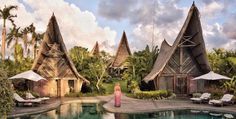 a woman standing in front of a pool surrounded by huts