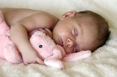 a baby sleeping with a pink teddy bear