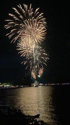 fireworks are lit up over the water at night