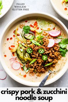 a bowl of soup with meat and veggies in it on a white table