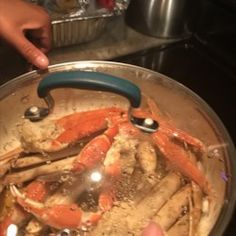 a person holding a pan full of crab legs