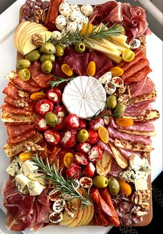 a platter filled with meats, cheese and olives on a white plate