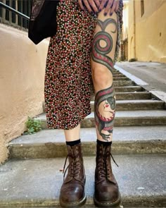 a woman with tattoos on her legs and leggings is standing in front of some steps