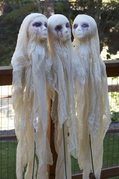 three white dolls with long hair and purple eyes are standing in front of a fence