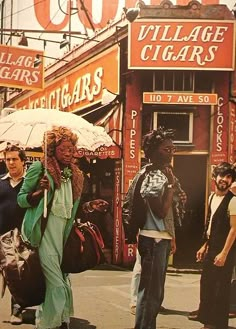 people walking down the street with umbrellas in front of stores and signs on buildings