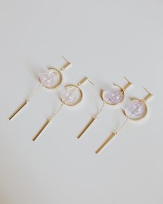 five pairs of earrings with gold posts and pink stones on them, all in different shapes