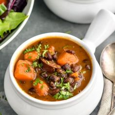 two bowls of soup with carrots, beans and greens