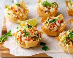 small appetizers are arranged on paper with limes and garnishes