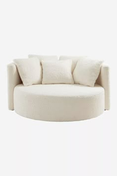 a white round couch with pillows on the top and bottom, sitting in front of a white background