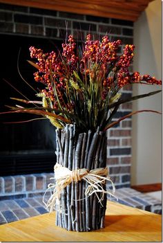 a wooden table topped with a vase filled with flowers next to a fire place mantle