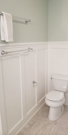 a white toilet sitting in a bathroom next to a sink and towel rack on the wall