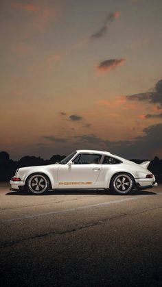 a white porsche parked in the middle of an empty parking lot at night with clouds overhead