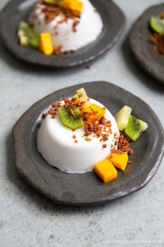 three desserts on black plates topped with kiwi, bananas and other toppings