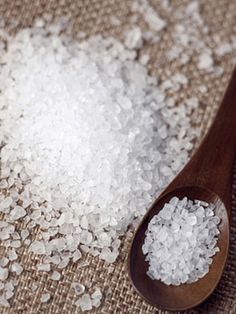 a wooden spoon filled with sea salt on top of a table