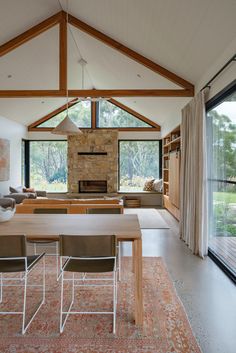 an open living room and dining area in a modern house with wood beams on the ceiling