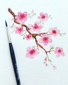 a watercolor painting of pink flowers on white paper with a black brush next to it