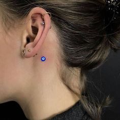 a woman's ear with two small blue dots on the back of her ear