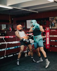 two men are boxing in the ring with one man wearing an orange helmet and blue shorts