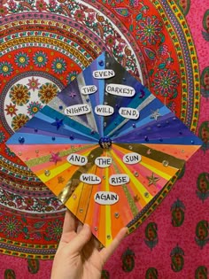 a hand holding up a colorful fan with words on it